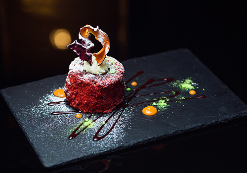 A fancy dessert on a slate dusted with icing sugar