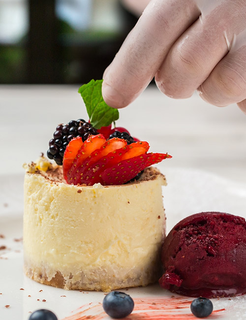 A hand adding finishing garnish to a dessert.